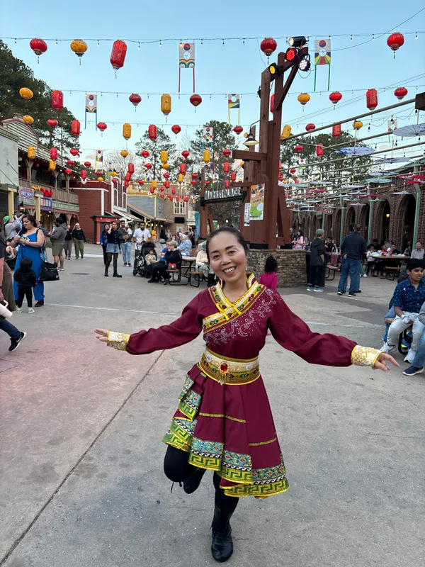 身着民族服装，在灯笼下张开双臂起舞
